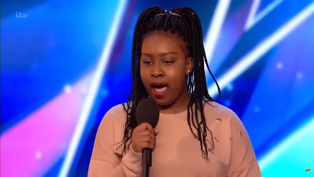 The moment she stepped onto the stage, the young woman boldly declared, "I am the greatest singer on Earth!" 1 girl step 2